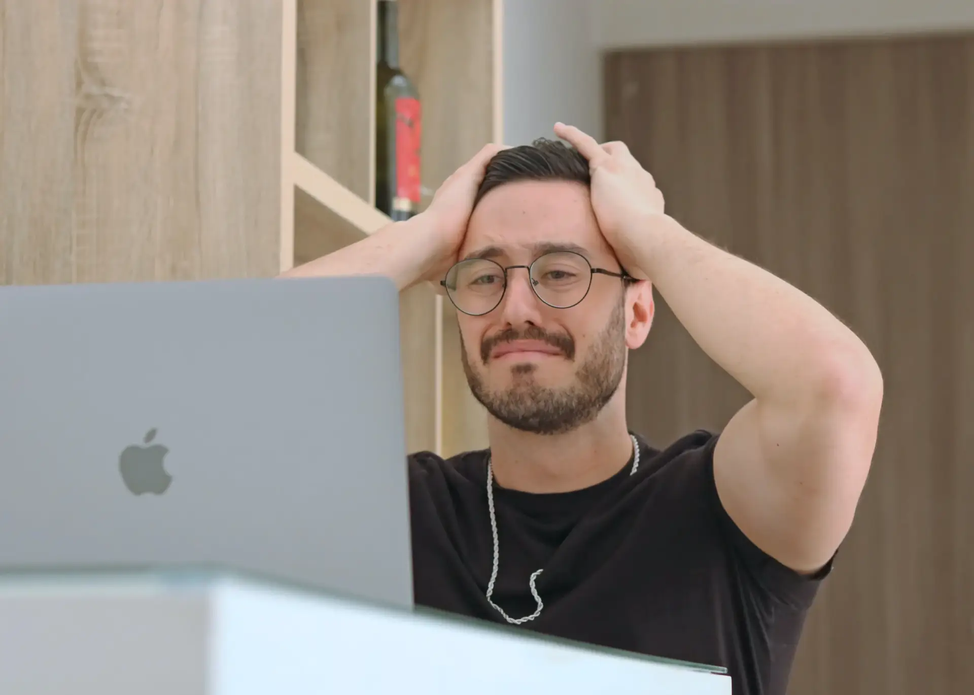 White male sitting in front of a laptop holding his head in his hands.